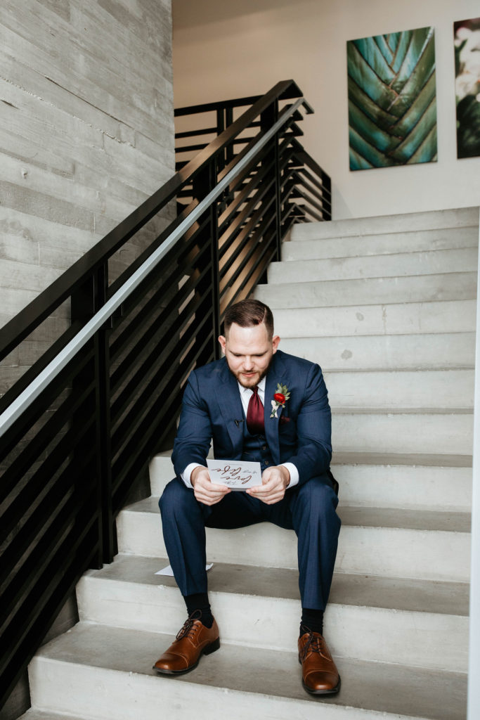 Groom reads letter from his bride on stairs